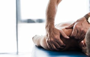 Close up of a person laying on the massage table with the therapist massaging the shoulder.