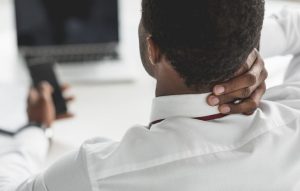 A man from the back holding his neck like he's in pain.