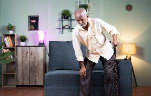 Man standing up and holding his knee as if he's in pain.